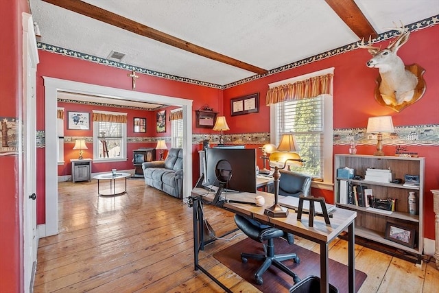 office space with beamed ceiling, visible vents, plenty of natural light, and hardwood / wood-style floors
