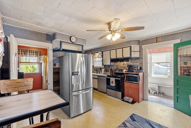 kitchen featuring decorative backsplash, light floors, ceiling fan, appliances with stainless steel finishes, and exhaust hood