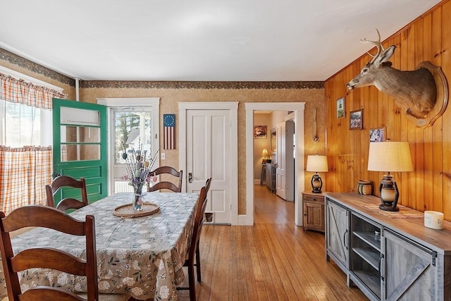 dining area featuring wooden walls, baseboards, and light wood-style flooring