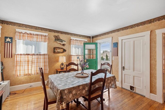 dining room featuring light wood-type flooring, baseboards, and wallpapered walls