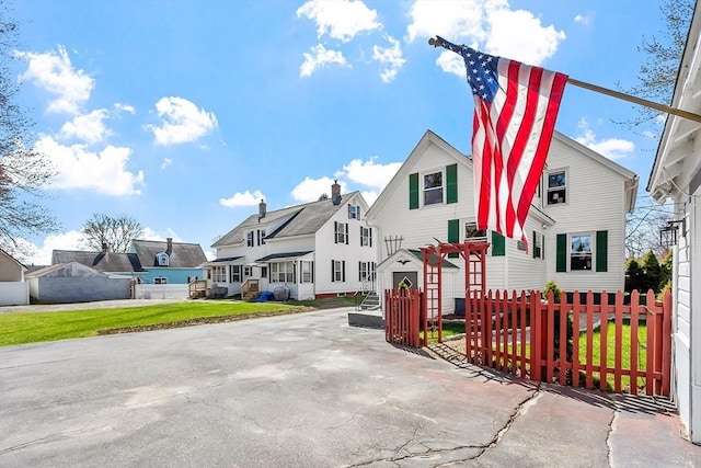 view of front of property with a residential view, a fenced front yard, and a front lawn