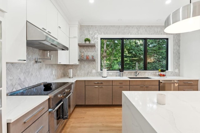 kitchen featuring appliances with stainless steel finishes, light stone counters, sink, light hardwood / wood-style flooring, and white cabinets