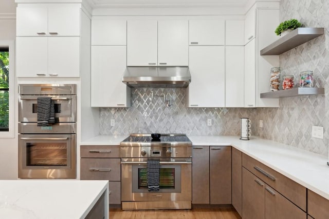 kitchen with backsplash, white cabinetry, and stainless steel appliances