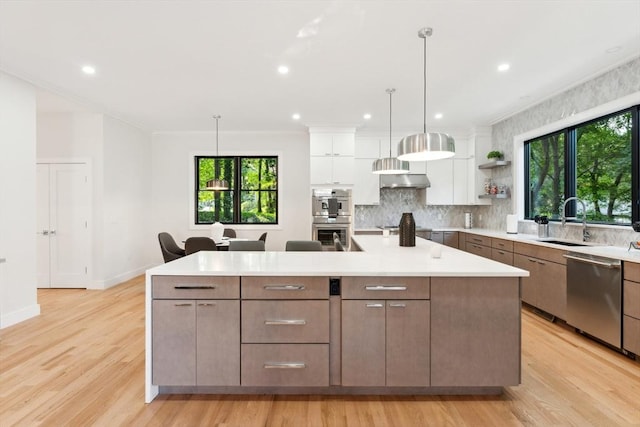 kitchen featuring appliances with stainless steel finishes, a spacious island, sink, white cabinets, and hanging light fixtures