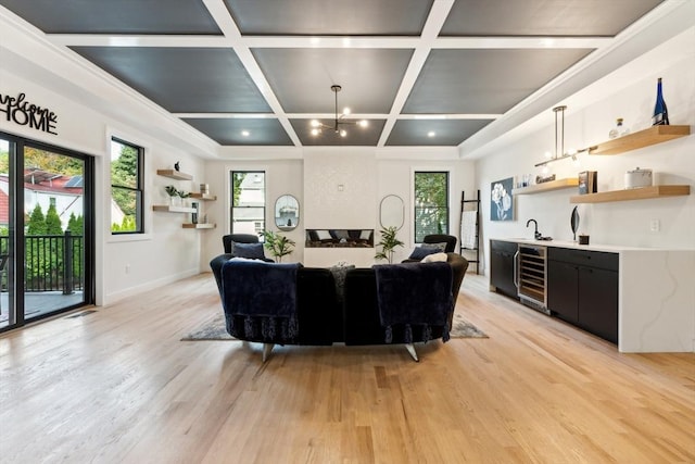 living room with light hardwood / wood-style floors, plenty of natural light, beverage cooler, and coffered ceiling