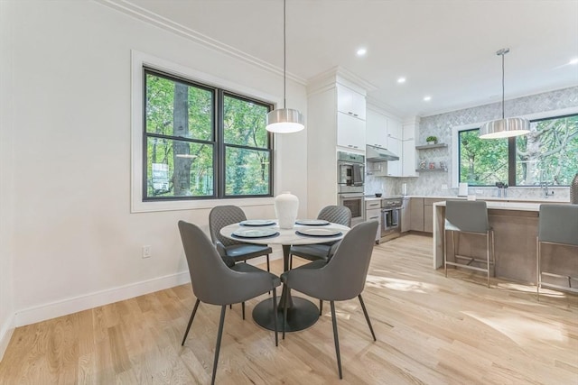 dining space featuring ornamental molding, light hardwood / wood-style flooring, and a healthy amount of sunlight