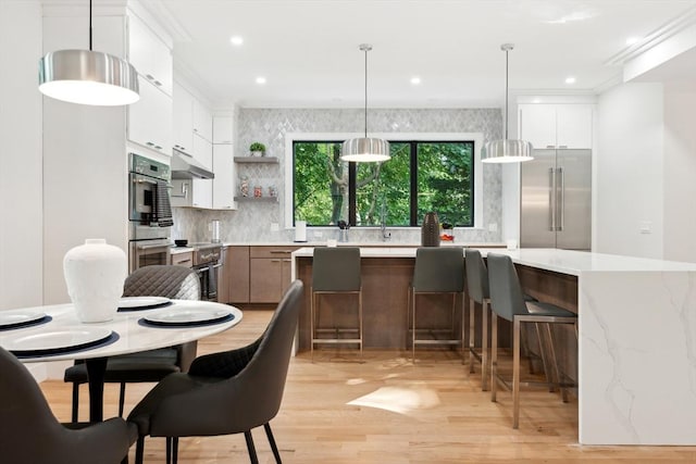 kitchen featuring light stone countertops, white cabinets, decorative light fixtures, and appliances with stainless steel finishes