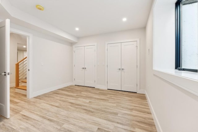 unfurnished bedroom with two closets and light hardwood / wood-style flooring