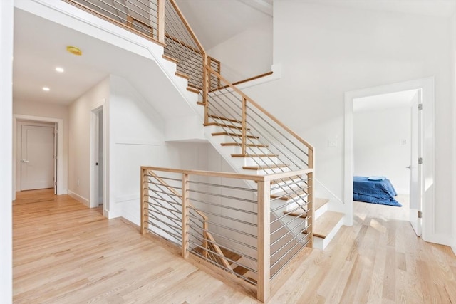 stairway featuring wood-type flooring and a high ceiling