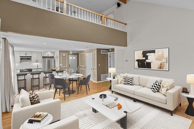 living room featuring visible vents, high vaulted ceiling, and light wood-type flooring