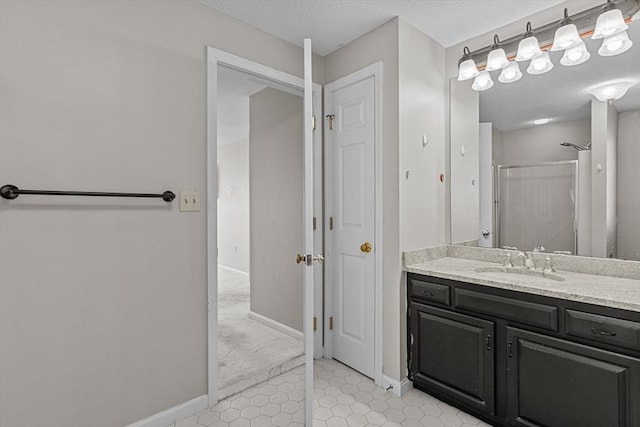 bathroom with a textured ceiling, tile patterned flooring, a shower with shower door, vanity, and baseboards