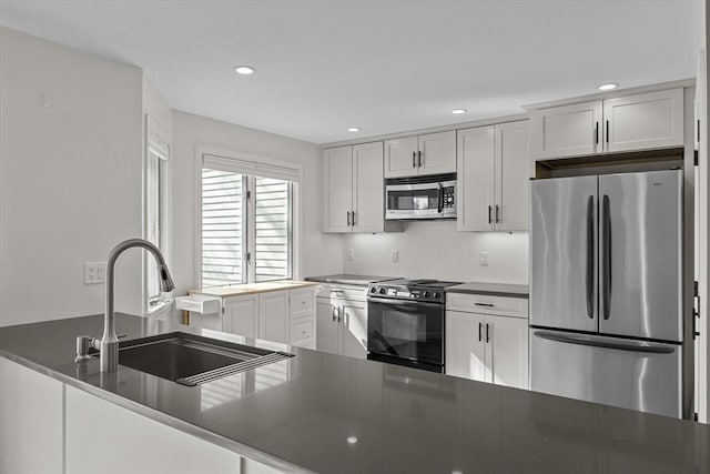 kitchen with a sink, appliances with stainless steel finishes, recessed lighting, and dark countertops
