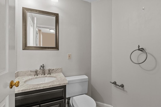 half bathroom with toilet, baseboards, and vanity