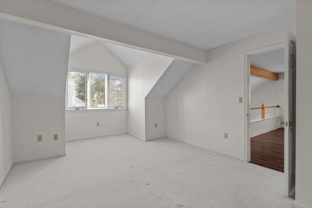 additional living space featuring baseboards, vaulted ceiling with beams, and carpet
