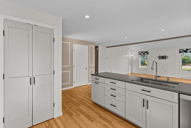 kitchen featuring dark countertops, recessed lighting, a sink, light wood-style flooring, and dishwasher