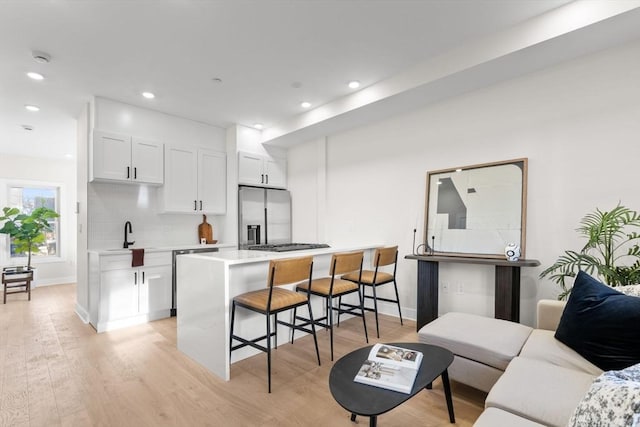 kitchen with a breakfast bar area, light countertops, appliances with stainless steel finishes, white cabinetry, and light wood-type flooring