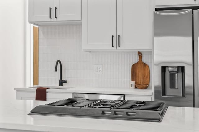 kitchen featuring stainless steel appliances, tasteful backsplash, a sink, and white cabinetry