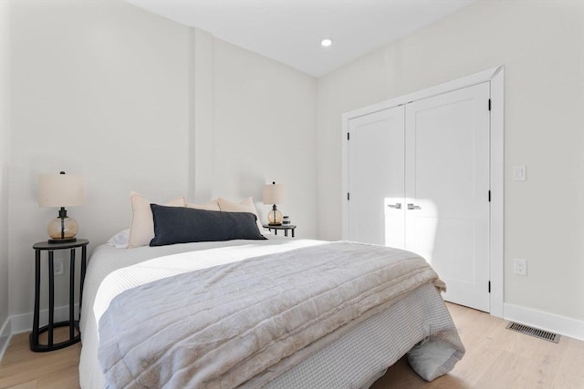 bedroom with baseboards, visible vents, light wood-type flooring, a closet, and recessed lighting