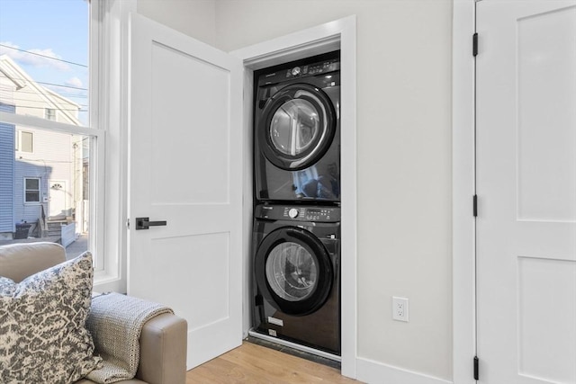 laundry area featuring laundry area, light wood finished floors, and stacked washer / dryer