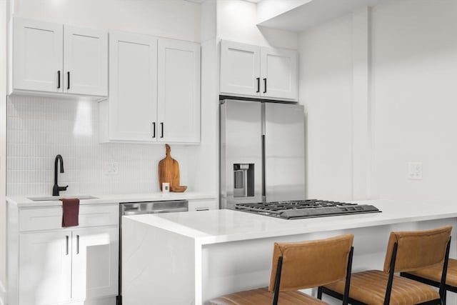 kitchen with stainless steel appliances, a breakfast bar area, a sink, and decorative backsplash