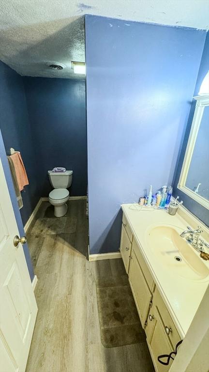 2 Altavesta Cir Unit A, Woburn, MA 01801 - bathroom with wood finished floors, vanity, toilet, baseboards, and a textured ceiling