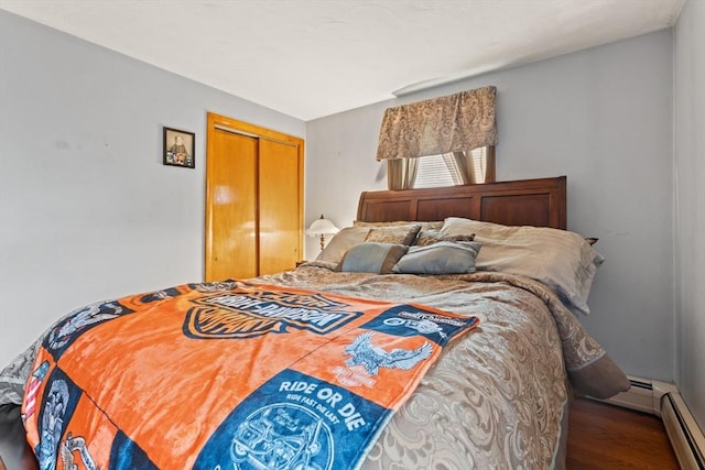 bedroom with a closet, a baseboard radiator, and wood finished floors
