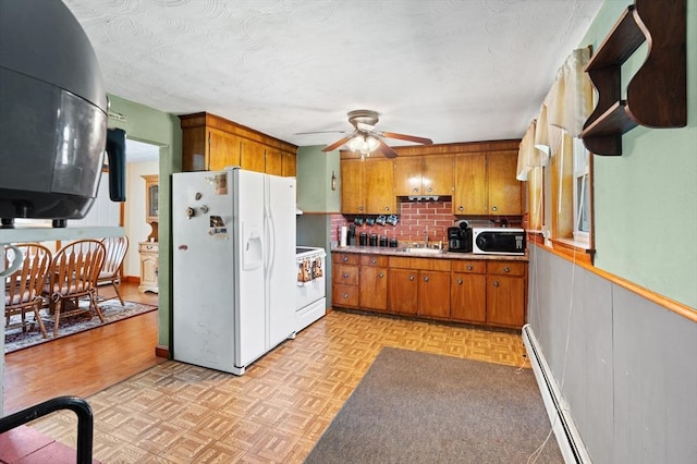 kitchen featuring ceiling fan, backsplash, brown cabinets, light countertops, and white appliances