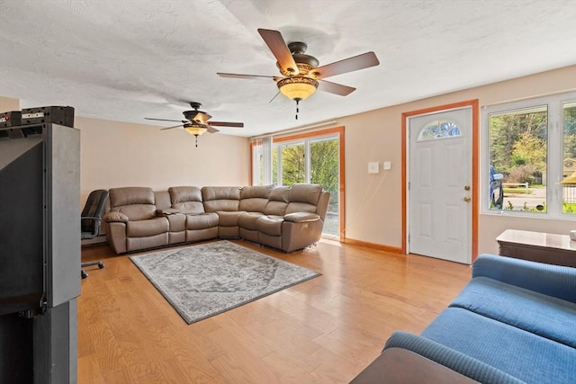 living room with baseboards, a ceiling fan, and light wood finished floors
