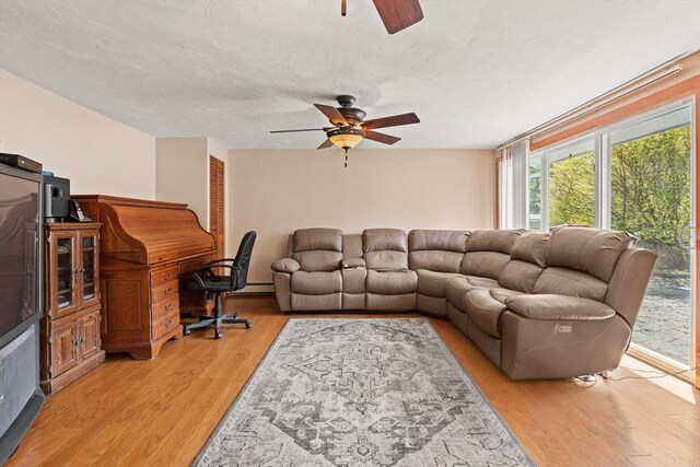 living room featuring a baseboard radiator, a ceiling fan, and light wood-style flooring