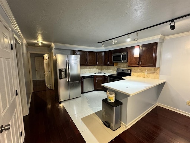 kitchen with backsplash, kitchen peninsula, ornamental molding, and stainless steel appliances