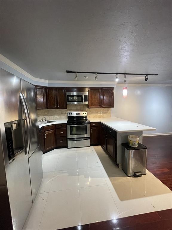 kitchen featuring dark brown cabinetry, sink, stainless steel appliances, decorative backsplash, and light tile patterned flooring