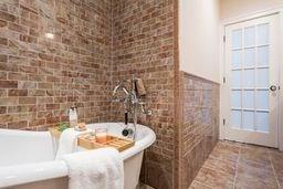 bathroom featuring brick wall and a freestanding bath