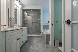 full bathroom with a stall shower, a garden tub, vanity, and concrete floors