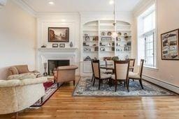 dining area featuring wood finished floors, a fireplace, ornamental molding, and a wealth of natural light