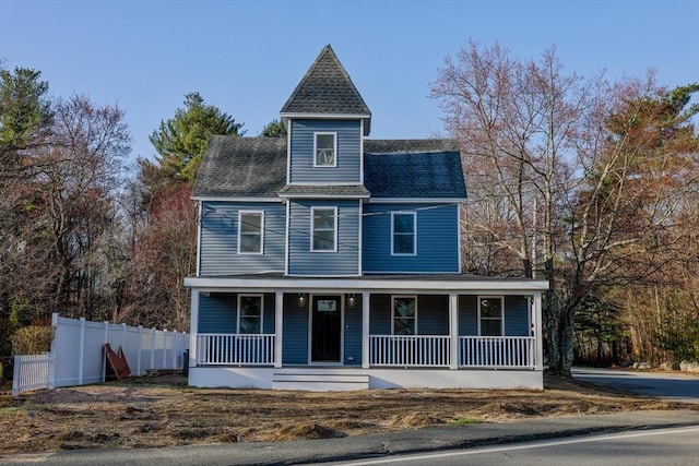 view of front facade with covered porch, fence, and roof with shingles
