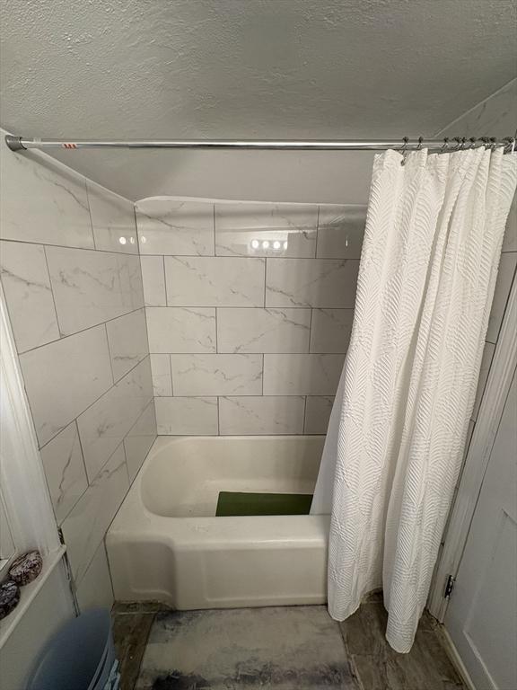 bathroom with shower / bath combo with shower curtain and a textured ceiling