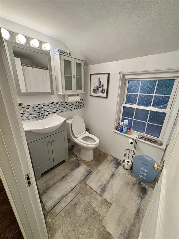 full bath featuring backsplash, a textured ceiling, vanity, and toilet