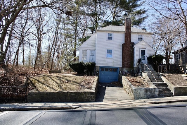 view of front facade with an attached garage, driveway, and a chimney