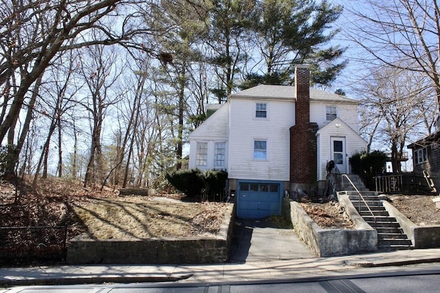 view of front of home with a garage, concrete driveway, and a chimney