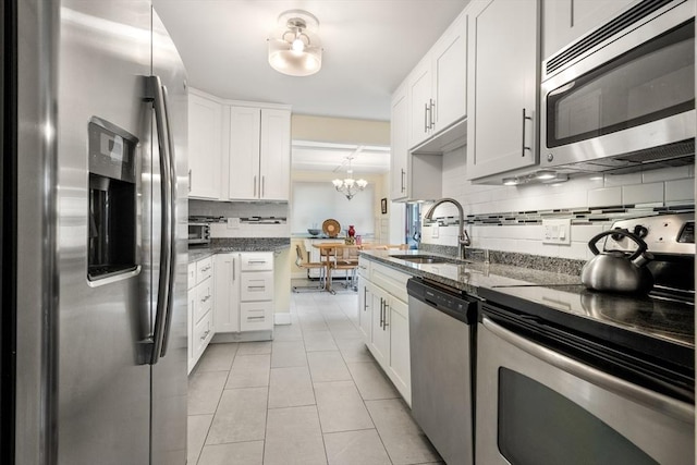 17 Chandler Rd, Malden, MA 02148 - kitchen featuring appliances with stainless steel finishes, a sink, backsplash, light tile patterned flooring, and dark stone countertops