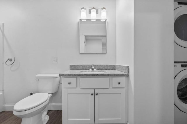 693 Western Ave Unit 404, Lynn, MA 01905 - bathroom featuring stacked washer / dryer, wood finished floors, toilet, vanity, and baseboards