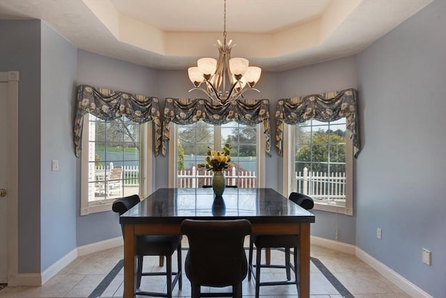 dining room with light tile patterned floors, baseboards, a tray ceiling, and a chandelier