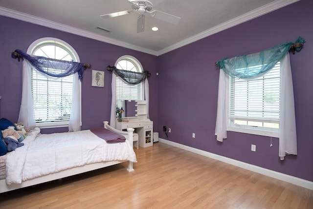 bedroom featuring visible vents, ornamental molding, wood finished floors, and multiple windows