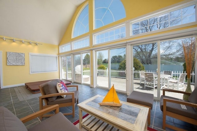 sunroom featuring track lighting, baseboards, and high vaulted ceiling