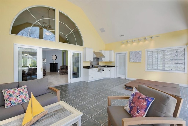 living area with dark tile patterned floors, rail lighting, and high vaulted ceiling