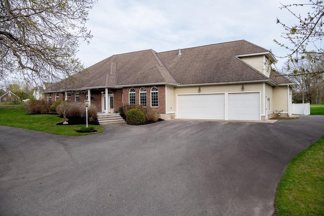 view of front of property featuring a garage, a front lawn, brick siding, a shingled roof, and driveway