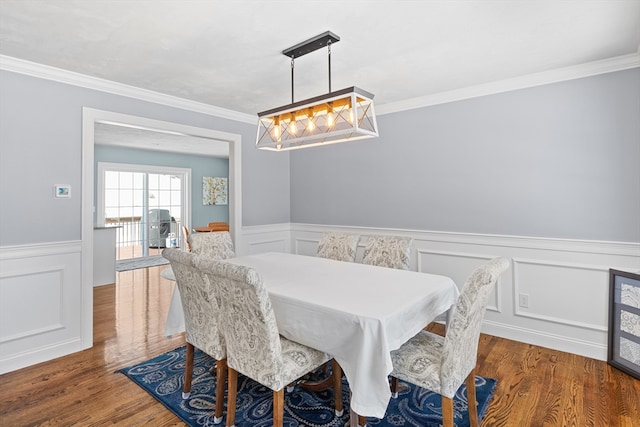 dining area with a wainscoted wall, ornamental molding, and wood finished floors