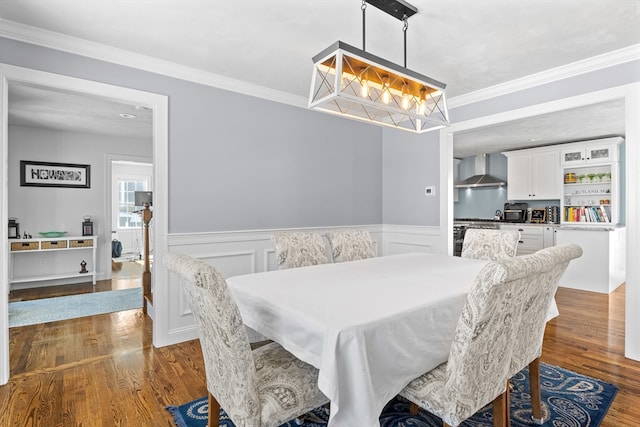 dining space with ornamental molding, wainscoting, and wood finished floors