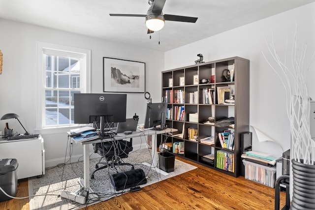 office area with a ceiling fan, baseboards, and wood finished floors