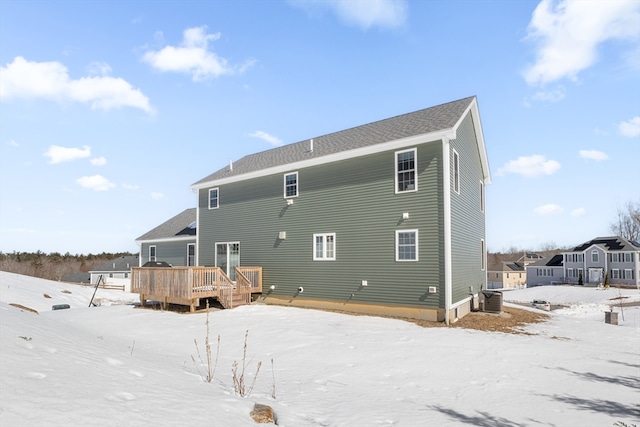 snow covered property with a wooden deck and central AC unit